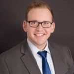 Head shot of Marc Gray, aptitude testing expert and Director of education of Odyssey College Prep. Marc wears a gray suit jacket and a blue tie.
